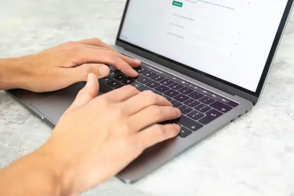 Dłonie piszą na laptopie. Może to być praca dla agencji copywriterskich, tworzenie treści lub analiza danych.